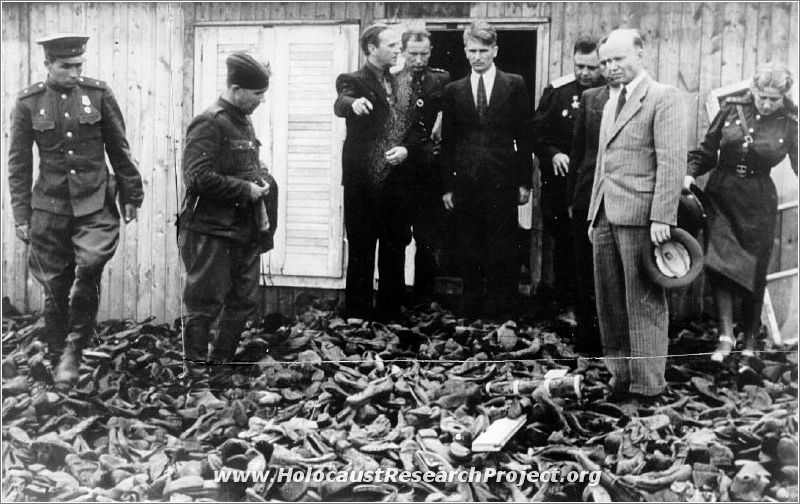 Members of the Soviet - Polish investigative commission in the Majdanek camp standing amid a pile of shoes of the camp's murdered victims.